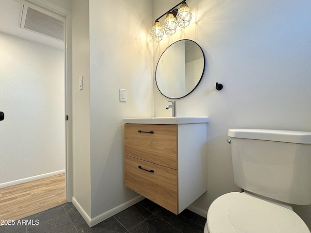 half bath with toilet, vanity, and baseboards