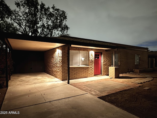 view of front facade with brick siding, driveway, and a carport