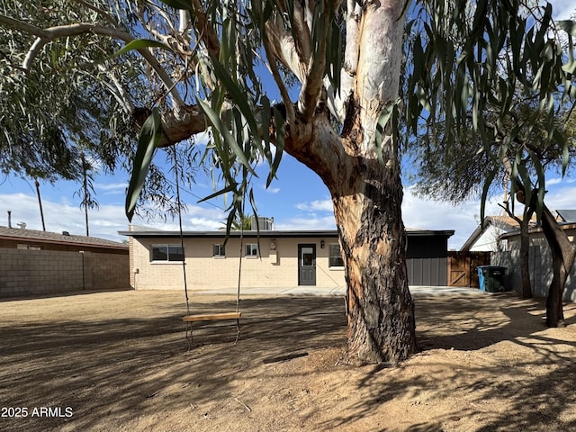 back of property featuring brick siding and fence