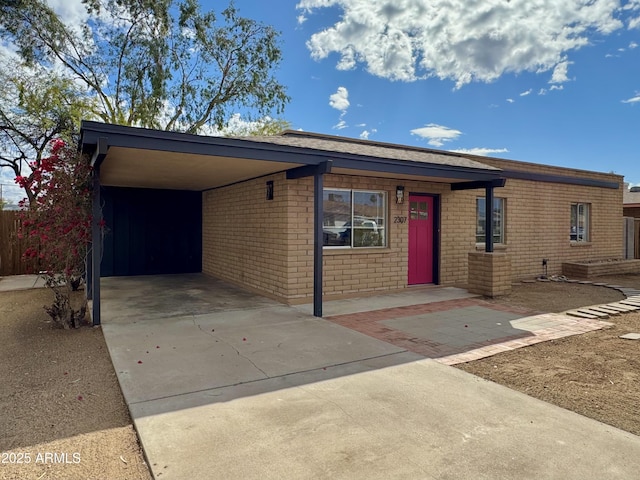 view of front facade featuring an attached carport, brick siding, and driveway