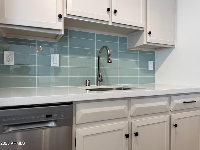 kitchen with white cabinetry, a sink, light countertops, stainless steel dishwasher, and backsplash