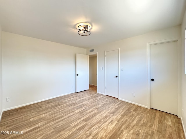 unfurnished bedroom with visible vents, baseboards, and light wood finished floors