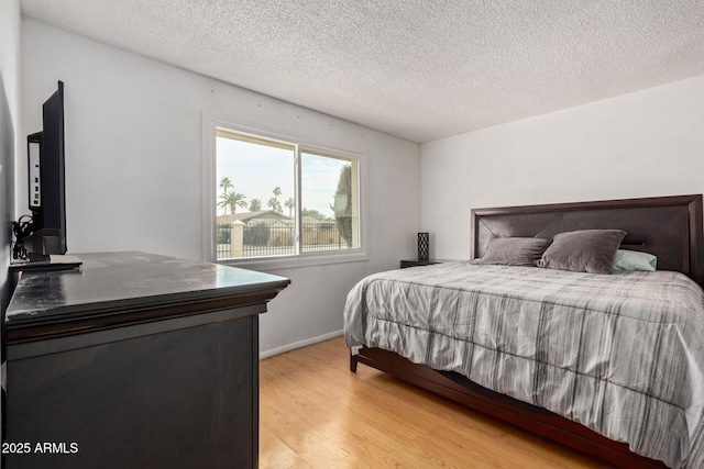 bedroom featuring a textured ceiling and light hardwood / wood-style flooring