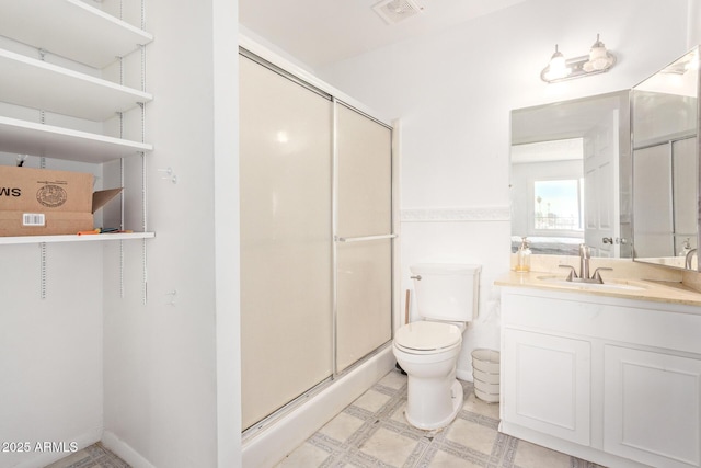 bathroom featuring toilet, vanity, and a shower with shower door