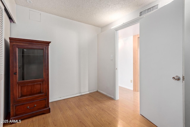 unfurnished room featuring a textured ceiling and light wood-type flooring