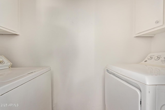 clothes washing area with cabinets and independent washer and dryer