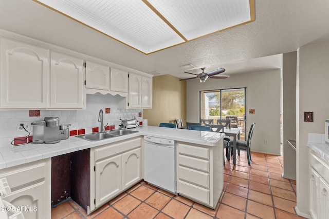 kitchen with dishwasher, a peninsula, a sink, and tile counters