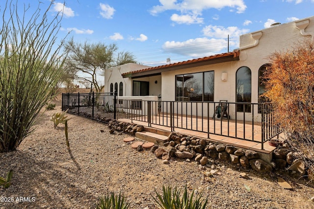 back of house featuring a tiled roof, fence, a patio, and stucco siding