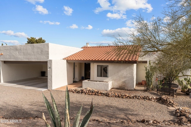 view of front of home with a patio area, a tile roof, a chimney, and stucco siding