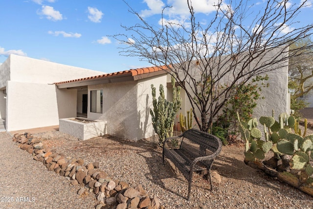 view of side of home with a tiled roof, a patio, and stucco siding