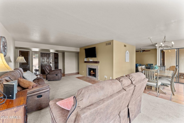 carpeted living area with a textured ceiling, ceiling fan with notable chandelier, a fireplace, and visible vents