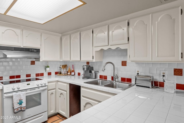 kitchen featuring white electric stove, tasteful backsplash, a sink, and under cabinet range hood