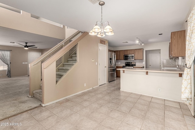 kitchen with tasteful backsplash, open floor plan, stainless steel appliances, light countertops, and a sink