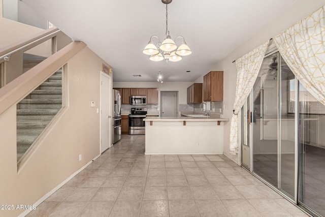 kitchen with brown cabinets, stainless steel appliances, light countertops, backsplash, and a sink