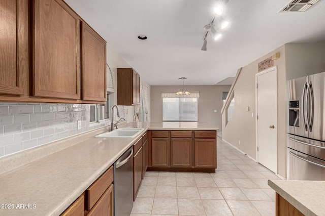 kitchen with visible vents, brown cabinetry, stainless steel appliances, light countertops, and a sink