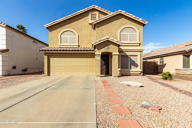 mediterranean / spanish house with a garage, driveway, a tile roof, and stucco siding