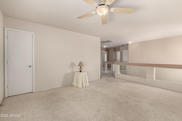 carpeted spare room with visible vents and a ceiling fan