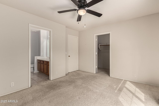 unfurnished bedroom with a closet, light colored carpet, connected bathroom, and a spacious closet