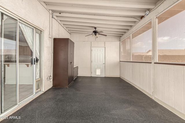 unfurnished sunroom featuring beam ceiling and a ceiling fan