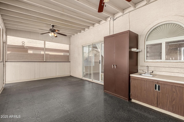 interior space featuring beam ceiling, a sink, and a ceiling fan