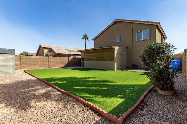 back of house featuring a sunroom, a fenced backyard, a lawn, and stucco siding