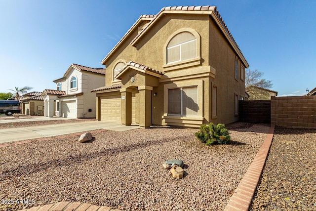 mediterranean / spanish home featuring concrete driveway, a tiled roof, an attached garage, fence, and stucco siding