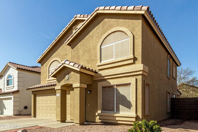 view of front facade with a garage, a tile roof, fence, and stucco siding