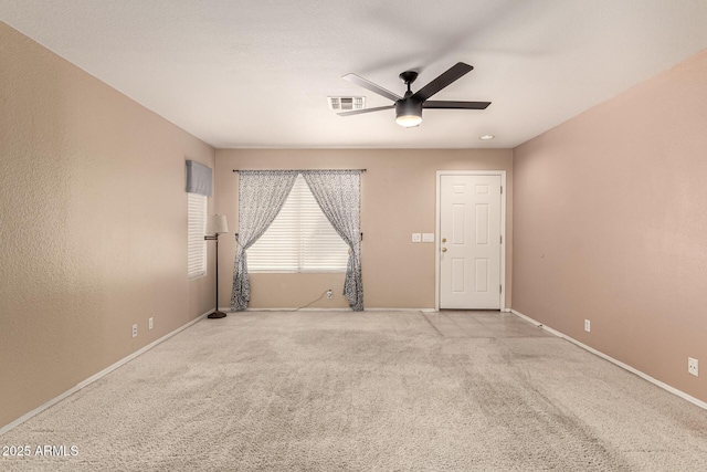 empty room with carpet floors, visible vents, ceiling fan, and baseboards