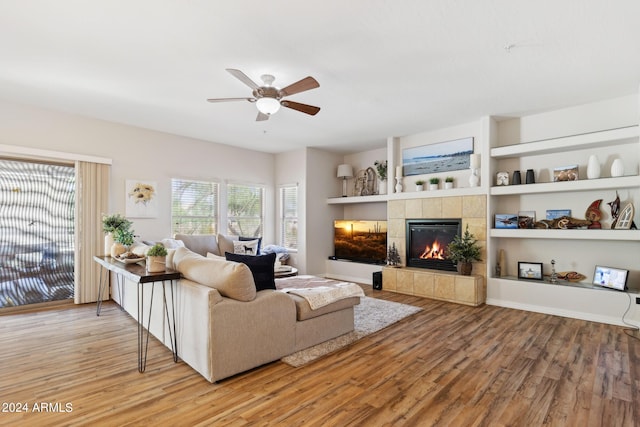 living room featuring a tiled fireplace, hardwood / wood-style floors, and ceiling fan