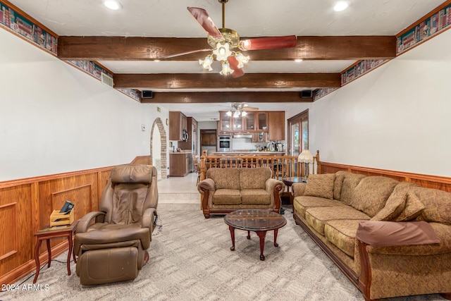 living room with ceiling fan, wooden walls, and beam ceiling