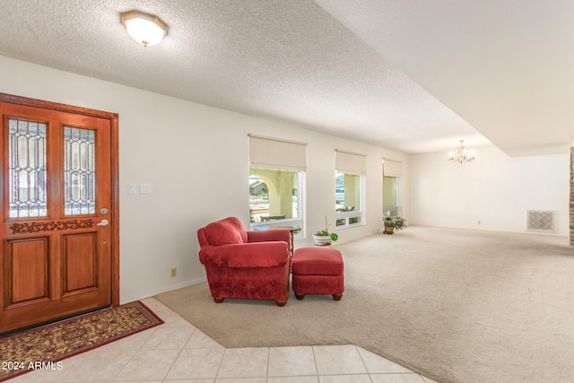 carpeted entrance foyer with an inviting chandelier and a textured ceiling