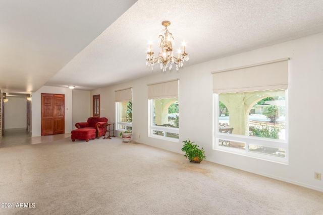 living area featuring an inviting chandelier, a textured ceiling, and carpet