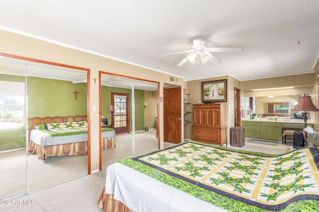 bedroom with ceiling fan, a textured ceiling, light colored carpet, and multiple closets