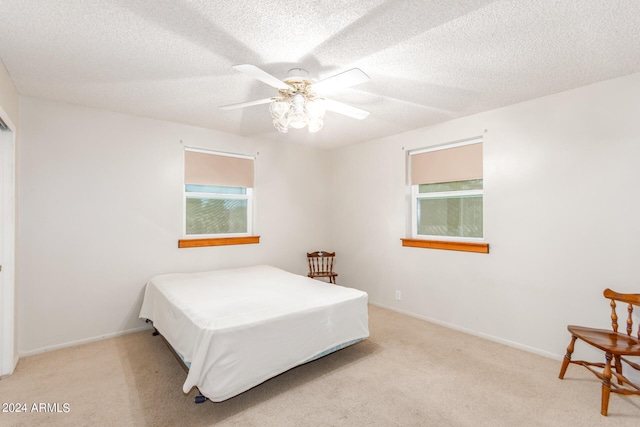 carpeted bedroom featuring ceiling fan, multiple windows, and a textured ceiling