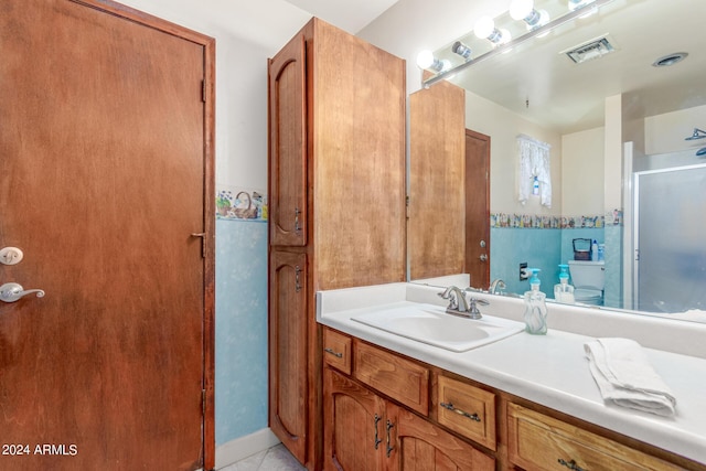 bathroom featuring vanity, a shower with shower door, tile patterned floors, and toilet