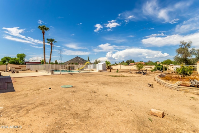 view of yard featuring a fenced in pool and a shed