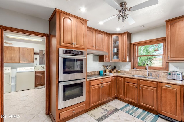 kitchen with sink, light tile patterned floors, black electric cooktop, stainless steel double oven, and washer and clothes dryer