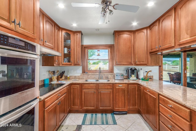 kitchen with sink, light tile patterned floors, double oven, light stone counters, and black electric stovetop