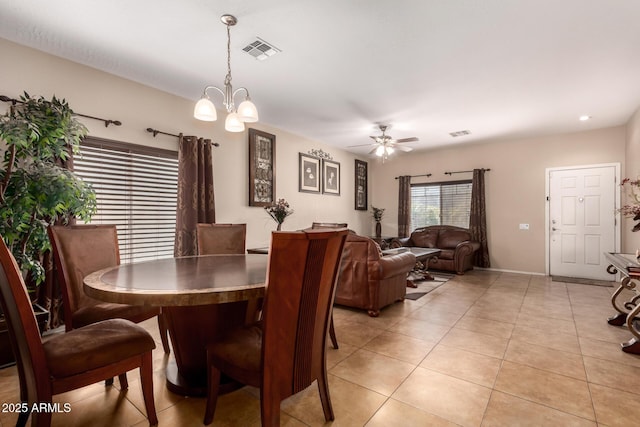 dining area featuring light tile patterned floors, ceiling fan with notable chandelier, and visible vents