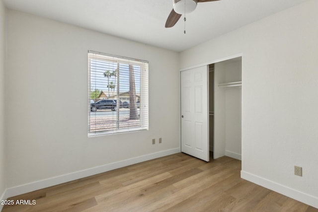 unfurnished bedroom featuring a closet, baseboards, ceiling fan, and light wood-style floors