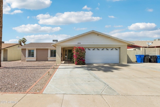 single story home featuring concrete driveway, brick siding, an attached garage, and fence