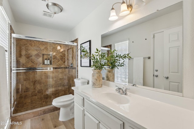 full bath with visible vents, vanity, wood finished floors, toilet, and a shower stall