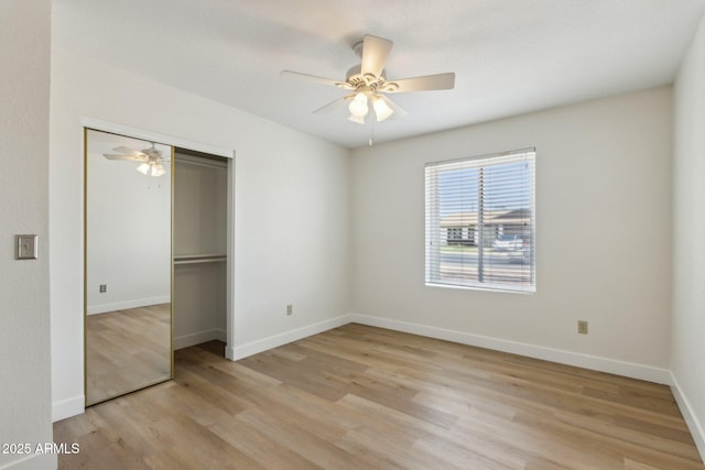 unfurnished bedroom featuring light wood-style floors, ceiling fan, baseboards, and a closet