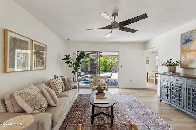 living room featuring baseboards, ceiling fan, and light wood-type flooring