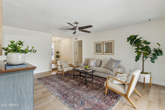 living room with light wood-type flooring, a ceiling fan, baseboards, and visible vents