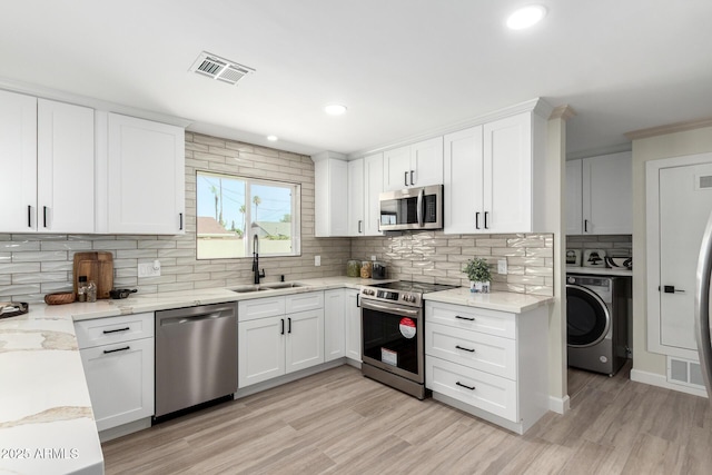 3050 E Cholla St E, Phoenix, AZ 85028 - kitchen with appliances with stainless steel finishes, washer / clothes dryer, tasteful backsplash, white cabinets, and light wood-style flooring