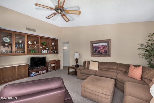 living room with lofted ceiling, ceiling fan, light colored carpet, and a textured ceiling