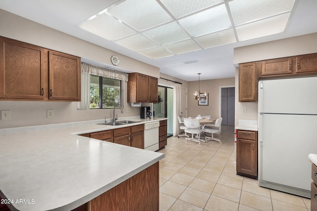 kitchen with white appliances, pendant lighting, light tile patterned floors, kitchen peninsula, and sink