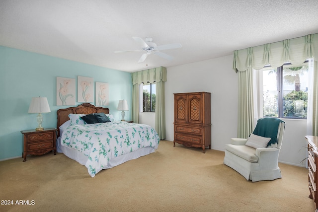 bedroom with ceiling fan, light carpet, and a textured ceiling