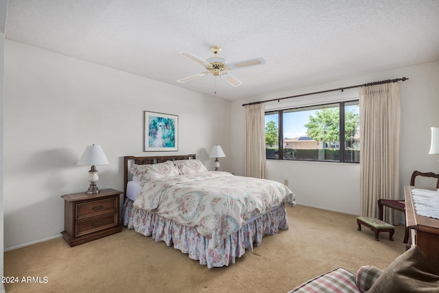 bedroom featuring ceiling fan, light carpet, and a textured ceiling